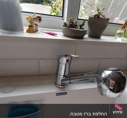 ברז מטבח כסוף עם כיור לבן ומסננת